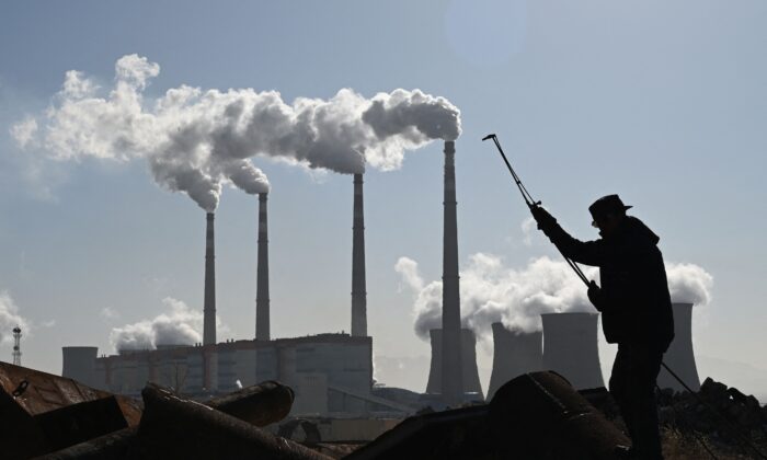 A worker uses a torch to cut steel pipes near the coal-powered Datang International Zhangjiakou Power Station at Zhangjiakou, Hebei Province, on November 12, 2021. (Greg Baker/AFP via Getty Images)