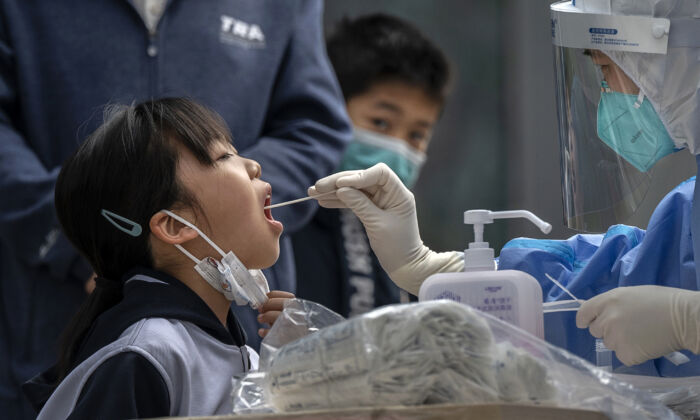 A young girl is given a nucleic acid test by a health worker at a makeshift COVID-19 testing site in Beijing on April 29, 2022. (Kevin Frayer/Getty Images)