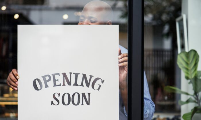 A man putting up a store 'Opening Soon' sign. (Rawpixel.com/Shutterstock)