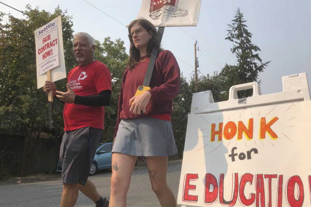 Guillermo Carvajal (L), a member of the support staff at Northgate Elementary School in Seattle, and Erin Carroll, an occupational therapist there, picket outside the building on the third day of a strike by the Seattle Education Association on Sept. 9, 2022. (Gene Johnson/AP Photo)
