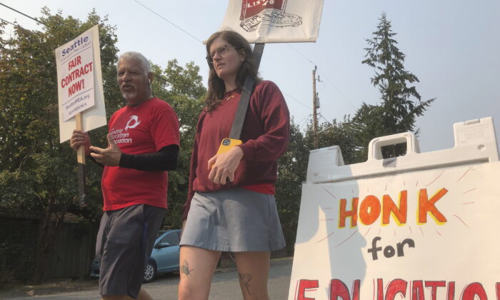 Guillermo Carvajal (L), a member of the support staff at Northgate Elementary School in Seattle, and Erin Carroll, an occupational therapist there, picket outside the building  on the third day of a strike by the Seattle Education Association on Sept. 9, 2022. (Gene Johnson/AP Photo)