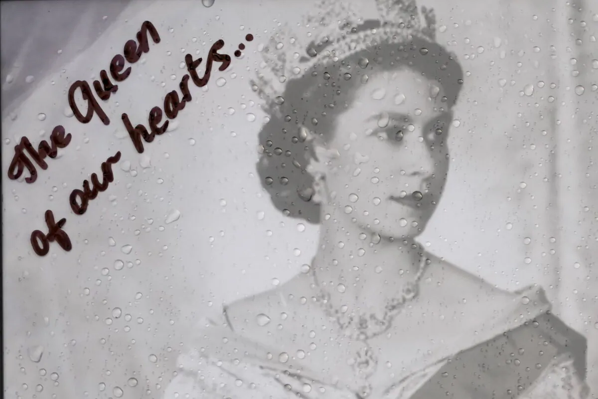 Raindrops are seen on a photograph of Queen Elizabeth II left at the gates of Buckingham Palace by a mourner in London on Sept. 9, 2022. (Kirsty Wigglesworth/AP Photo)