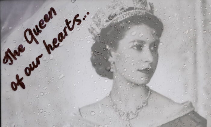 Raindrops are seen on a photograph of Queen Elizabeth II left at the gates of Buckingham Palace by a mourner in London on Sept. 9, 2022. (Kirsty Wigglesworth/AP Photo)