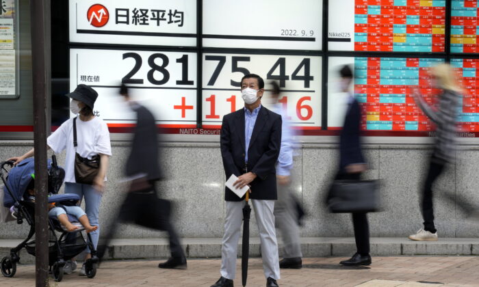 A person wearing a protective mask stands in front of an electronic stock board showing Japan's Nikkei 225 index at a securities firm, in Tokyo, Japan, on Sept. 9, 2022. (Eugene Hoshiko/AP Photo)