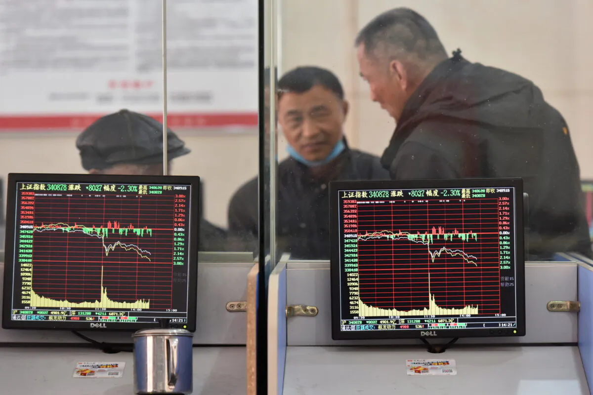 Investors are seen behind screens displaying stock information at a brokerage house in Fuyang, Anhui Province, China, on Feb. 24, 2022. (China Daily via Reuters)