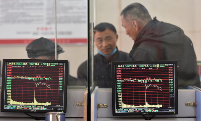 Investors are seen behind screens displaying stock information at a brokerage house in Fuyang, Anhui Province, China, on Feb. 24, 2022. (China Daily via Reuters)
