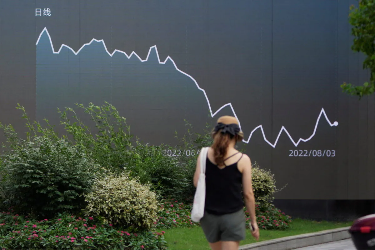 A pedestrian walks past a giant display showing a stock graph, in Shanghai on Aug. 3, 2022. (Aly Song/Reuters)