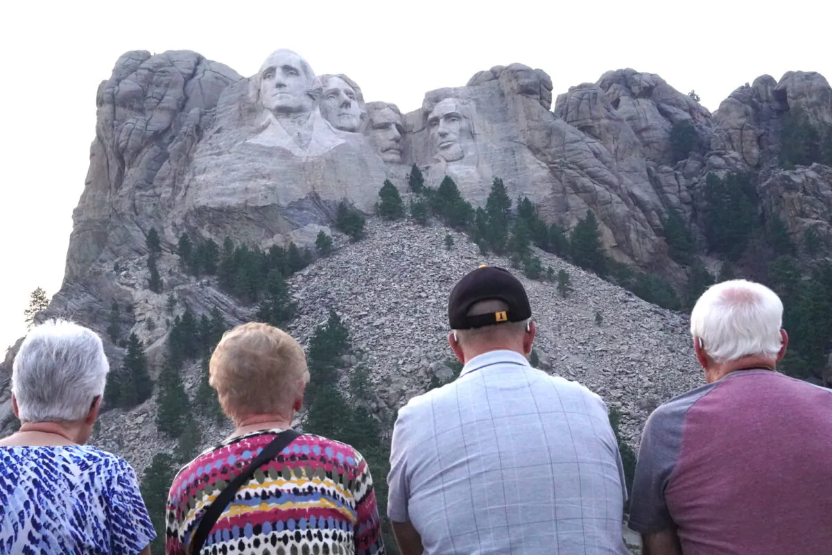Four visitors to Mount Rushmore gaze at the national monument in Keystone, S.D., on Sept. 7, 2022. (Allan Stein/The Epoch Times)