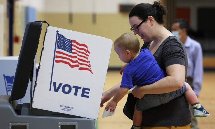 A voter casts her ballot with her child at a polling station at Rose Hill Elementary School during the midterm primary election on June 21, 2022, in Alexandria, Virginia. (Alex Wong/Getty Images)