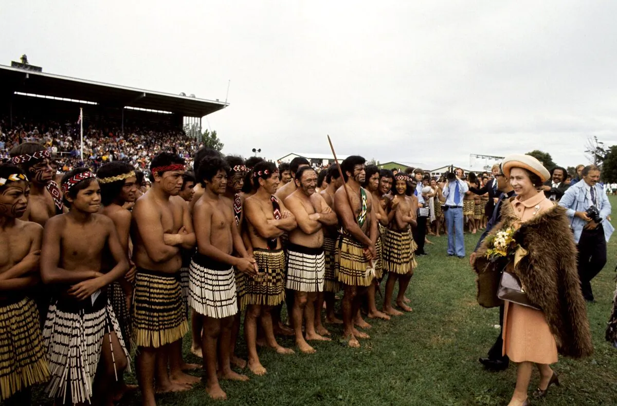 Queen Elizabeth II, wearing a cloak of brown kiwi feathers, meets Maori 'warriors' at Rugby Park in Gisborne, New Zealand on Feb. 26, 1977 (PA)