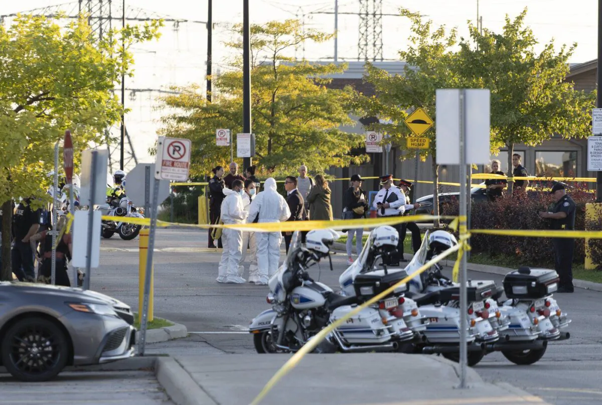Police vehicles and officers are seen behind tape at a scene in Mississauga, Ont., on Sept. 12, 2022. (The Canadian Press/Arlyn McAdorey)