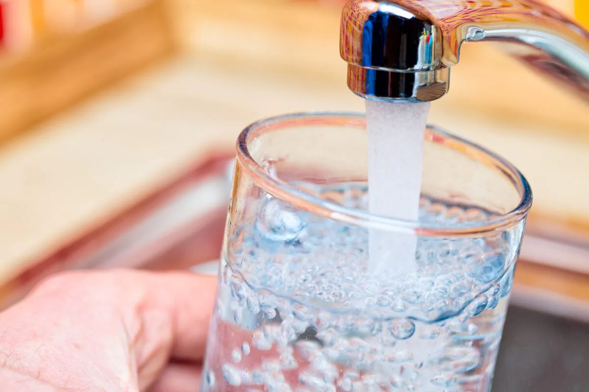 Closeup shot of a man pouring a glass of fresh water from a kitchen faucet. (Dmitry Naumov/Shutterstock)