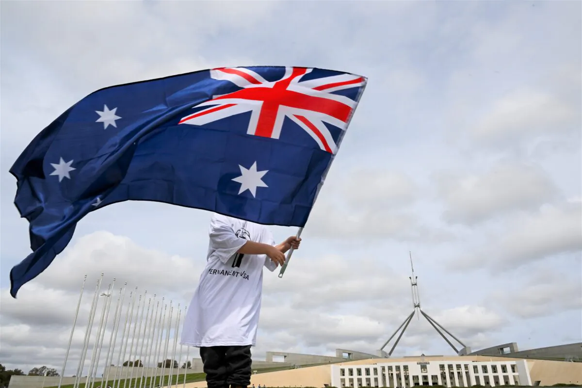 A young boy waves an Australian flag during a rally for refugee rights outside Parliament House in Canberra, Australia, on Sept. 6, 2022. (AAP Image/Lukas Coch)