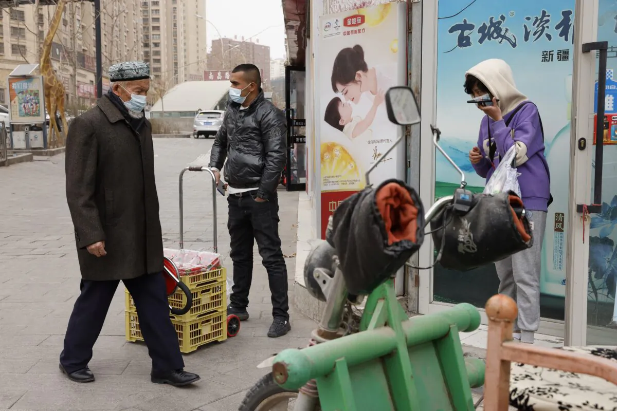 Residents wearing masks walk along the streets of Aksu in western China's Xinjiang region on March 18, 2021. (Ng Han Guan/AP Photo)