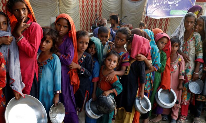 Flood victims gather to receive food handout in a camp, following rains and floods during the monsoon season in Sehwan, Pakistan, on Sept. 14, 2022. (Akhtar Soomro/Reuters)