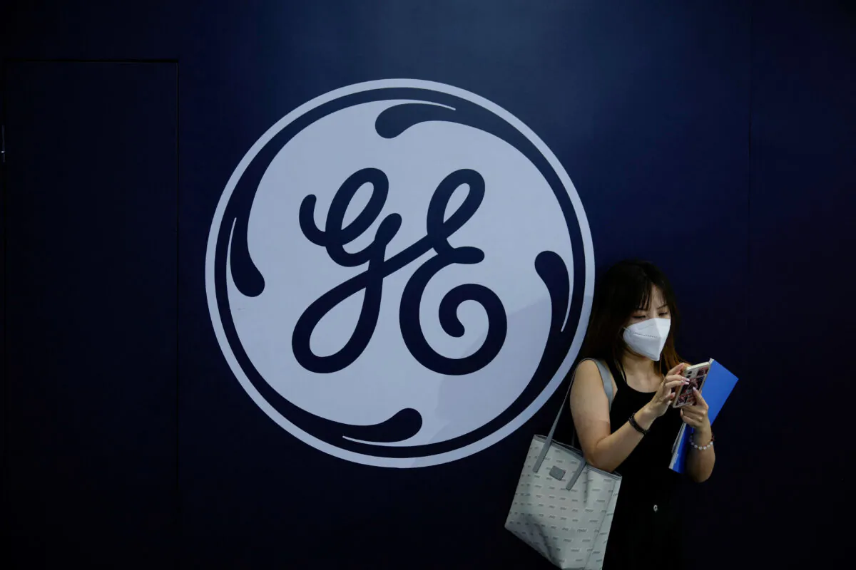 A woman stands in front of a General Electric (GE) sign during World Artificial Intelligence Conference in Shanghai on Sept. 1, 2022. (Aly Song/Reuters)