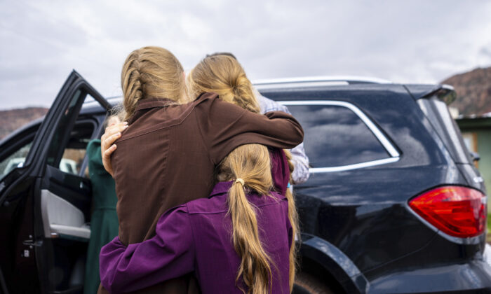 Three girls embrace before they are removed from the home of Samuel Bateman, following his arrest in Colorado City, Ariz., on Sept. 14, 2022. (Trent Nelson/The Salt Lake Tribune via AP)