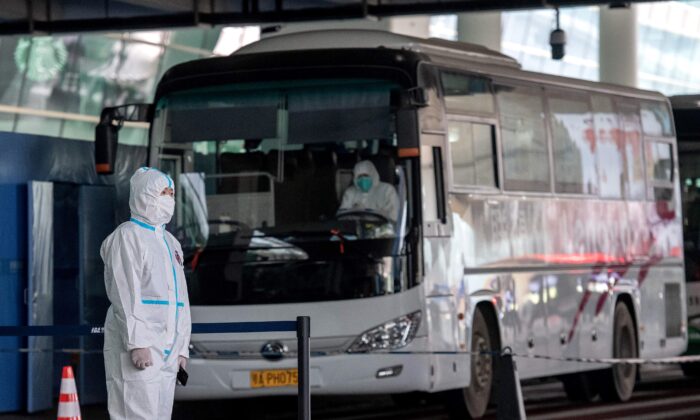A health worker wearing a personal protection suit stands next to a bus used to transport people to COVID-19 quarantine in China in a file photo. (Nicolas Asfouri/AFP via Getty Images)