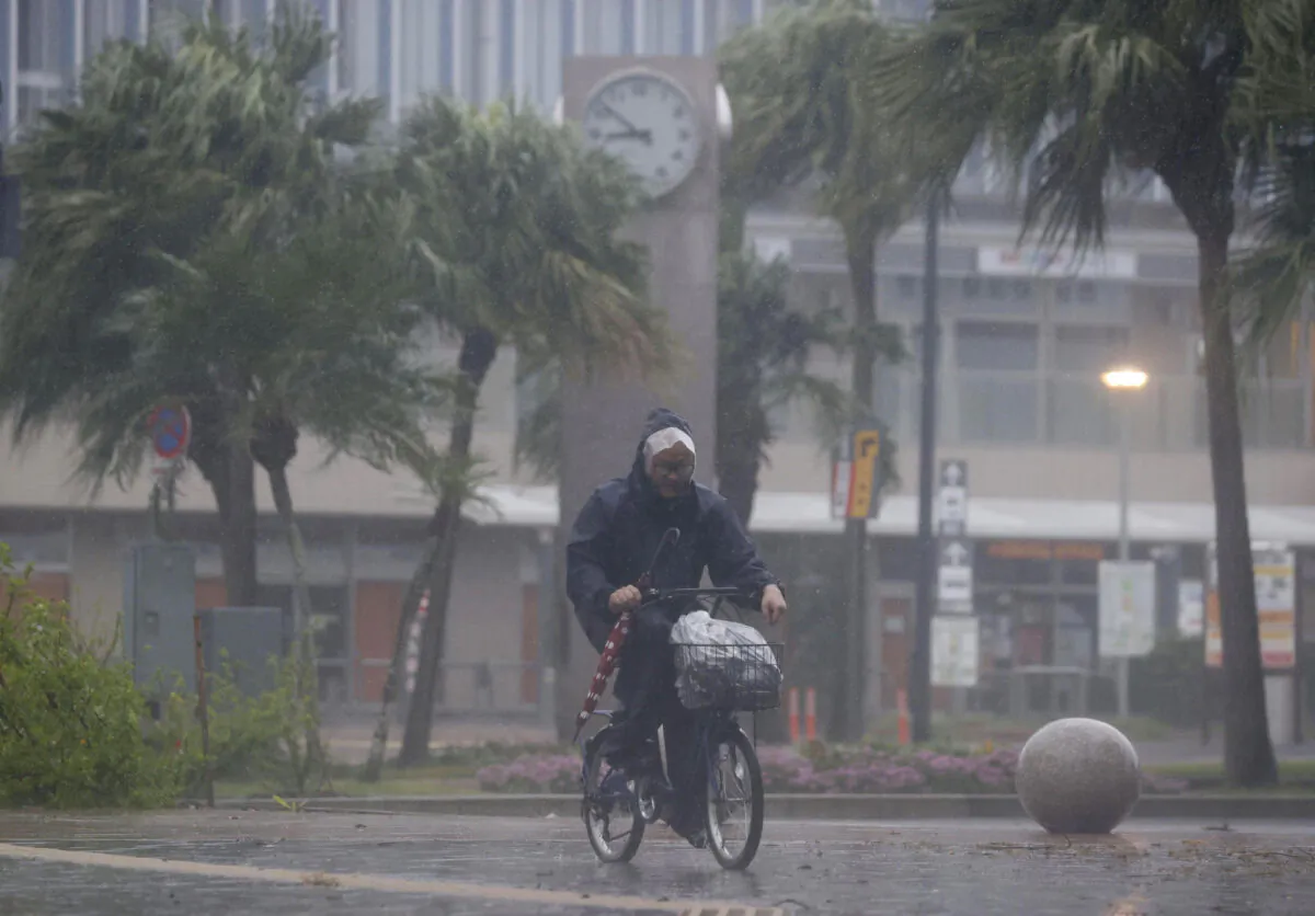 A man on a bicycle makes his way through the rain in Miyazaki, southern Japan, on Sept. 18, 2022, as Typhoon Nanmadol lashed the region with strong winds and heavy rain. (Kyodo News via AP)