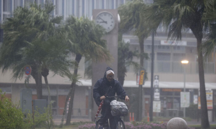 2022 年 9 月 18 日，日本南部宫崎市，一名骑自行车的男子在雨中跋涉，台风南马多以强风和大雨袭击了该地区。  （通过美联社的共同社新闻）