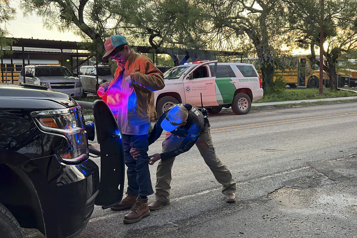 A Kinney County sheriff’s deputy searches a man during his arrest for smuggling illegal immigrants from the U.S.–Mexico border, through Brackettville, Texas, on Aug. 26, 2022. (Charlotte Cuthbertson/The Epoch Times)