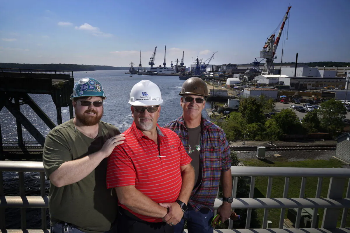 Tom Stevens (C), director of ground assembly at Navy shipbuilder Bath Iron Works, poses with his son Shane Stevens (L) and Tim Garland in Bath, Maine, on Aug. 30, 2022. (Robert F. Bukaty/AP Photo)