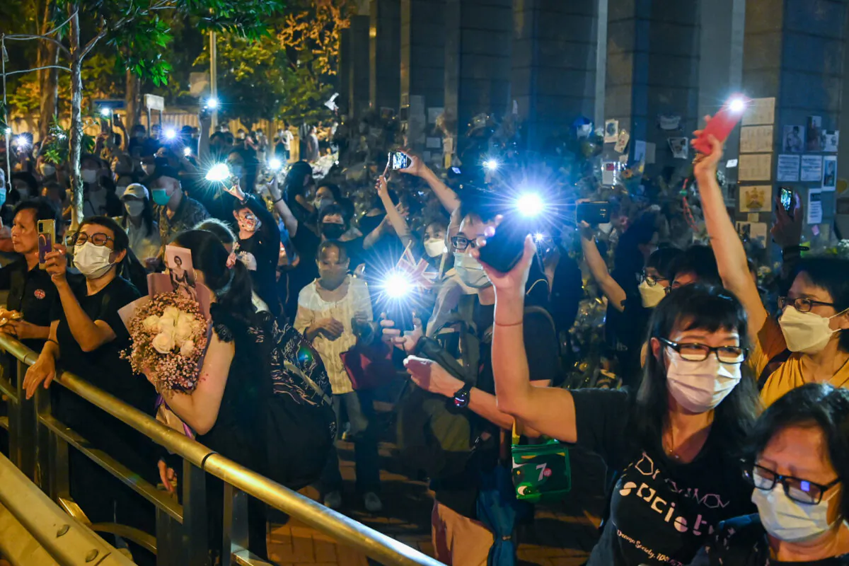 Members of the public mourn the passing of Queen Elizabeth II with flowers and candles outside the British Consulate General in Hong Kong on Sept. 19, 2022. (Sung Pi-lung/The Epoch Times)
