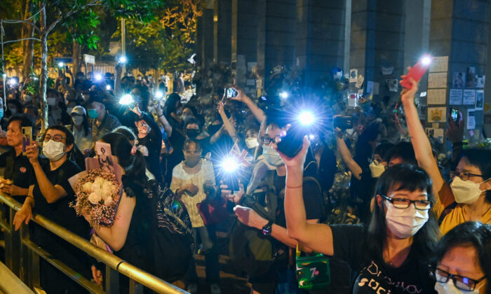 Members of the public mourn the passing of Queen Elizabeth II with flowers and candles outside the British Consulate General in Hong Kong on Sept. 19, 2022. (Sung Pi-lung/The Epoch Times)
