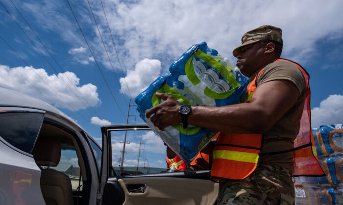 A member of the National Guard places a case of water in the back of a car at the State Fair Grounds in Jackson, Mississippi, on Sept. 2, 2022. (Seth Herald/AFP via Getty Images)