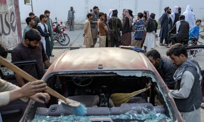 Afghan people clean a car that was damaged by an explosion in Kabul, Afghanistan, on Sept. 21, 2022. (Ebrahim Noroozi/AP Photo)