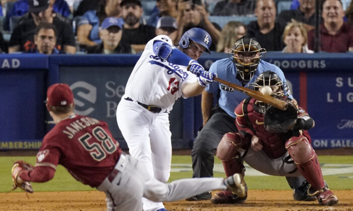 Los Angeles Dodgers' Max Muncy, second from left, hits a two-run home run as Arizona Diamondbacks relief pitcher Drey Jameson, left, watches along with catcher Carson Kelly, right, and home plate umpire Angel Hernandez during the sixth inning of a baseball game in Los Angeles, on Sept. 20, 2022. (Mark J. Terrill/AP Photo)