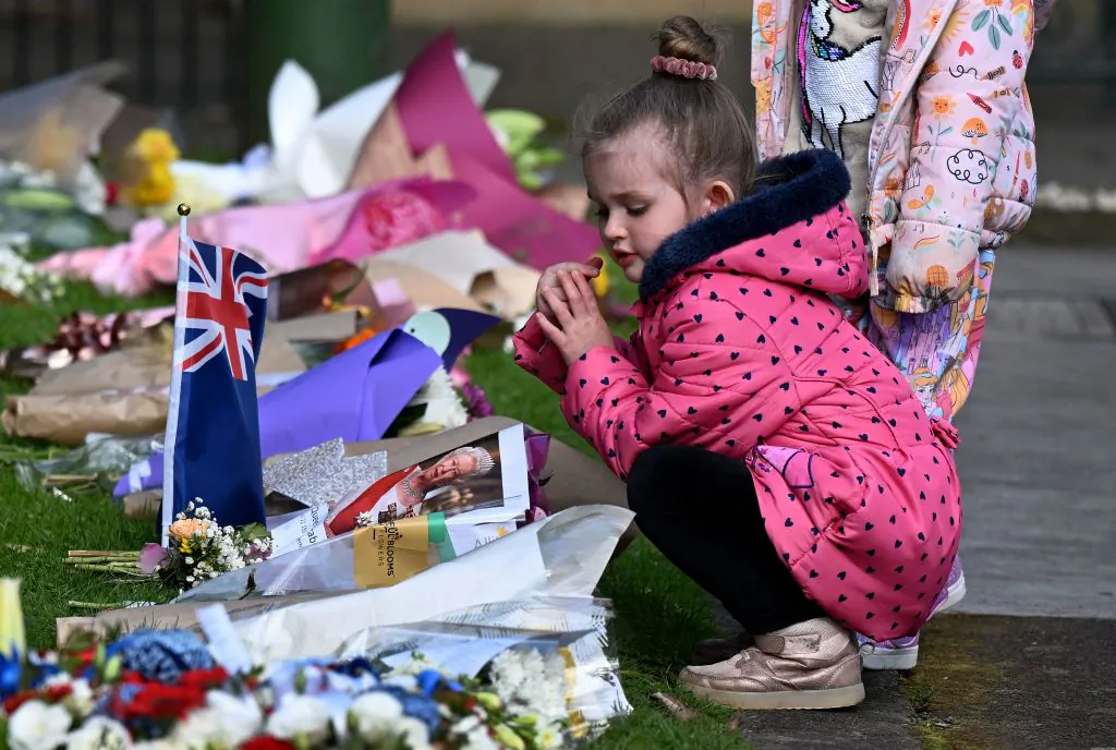 Children lay flowers outside Government House following the passing of Britain's Queen Elizabeth II in Melbourne, Australia, on Sept. 10, 2022. (William West/AFP via Getty Images)