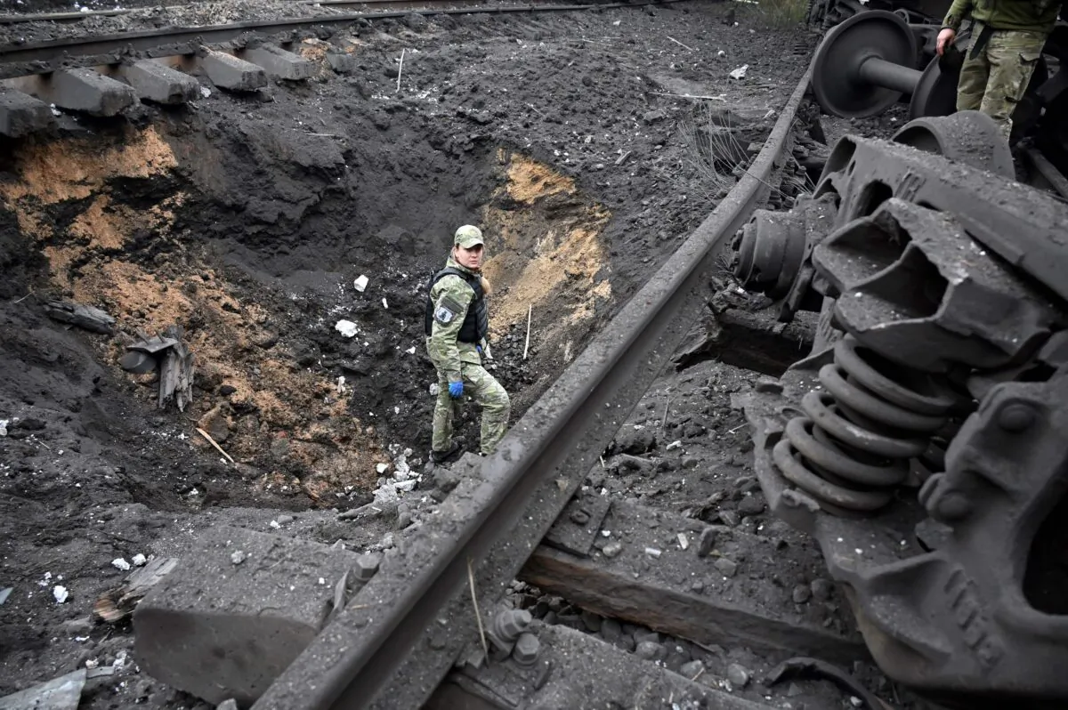 A forensic explosives expert examines a crater from a missile explosion at a freight railway station in Kharkiv, Ukraine on Sept. 21, 2022, amid Russia's military invasion of the country. (Sergey Bobok/AFP via Getty Images)