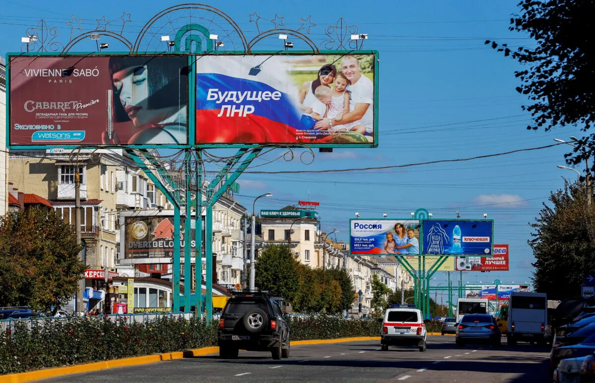 Vehicles drive past advertising boards, including panels displaying pro-Russian slogans, on a street in Luhansk, Ukraine, on Sept. 20, 2022. (Alexander Ermochenko/Reuters)