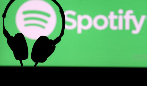A headset is seen in front of a screen projection of Spotify logo, in this picture illustration