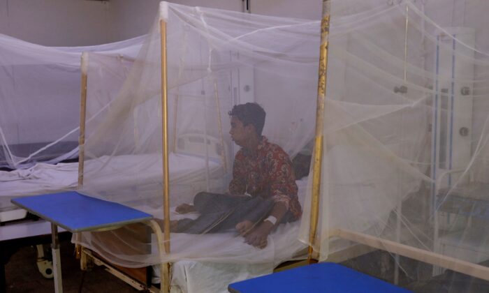 A patient suffering from dengue fever sits under a mosquito net inside a dengue and malaria ward at the Sindh Government Services Hospital in Karachi, Pakistan, on Sept. 21, 2022. (Akhtar Soomro/Reuters)