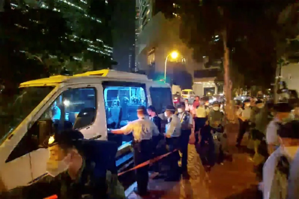Police put the man (C) who played songs on a harmonica into police van, outside the British Consulate in Hong Kong, on Sept. 19, 2022, in this image made from video. (Patreon @Boomhead via AP)