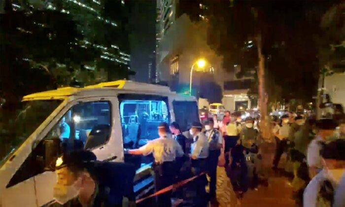 Police put the man (C) who played songs on a harmonica into police van, outside the British Consulate in Hong Kong, on Sept. 19, 2022, in this image made from video. (Patreon @Boomhead via AP)