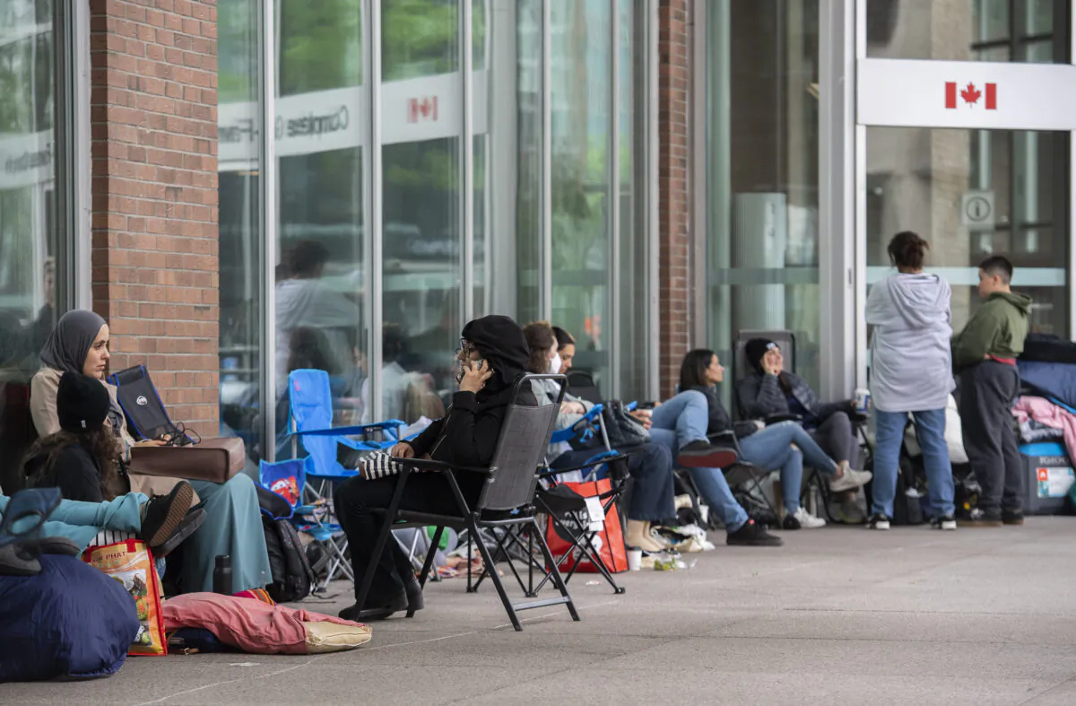 People line up outside the Guy Favreau federal building while waiting to apply for a passport in Montreal on June 21, 2022. (Graham Hughes/The Canadian Press)