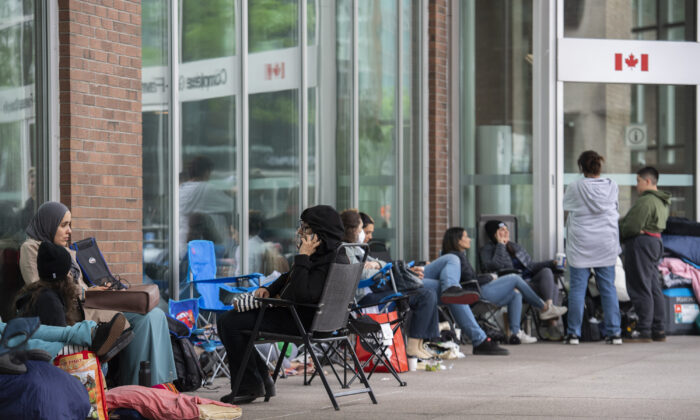 People line up outside the Guy Favreau federal building while waiting to apply for a passport in Montreal on June 21, 2022. (Graham Hughes/The Canadian Press)