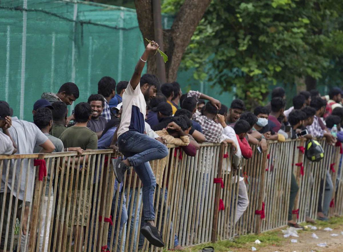 A man jumps a railing to take a break as people line up to buy tickets for the third Twenty20 cricket match between India and Australia at Gymkhana grounds in Hyderabad, India, on Sept. 22, 2022. (Mahesh Kumar A./AP Photo)