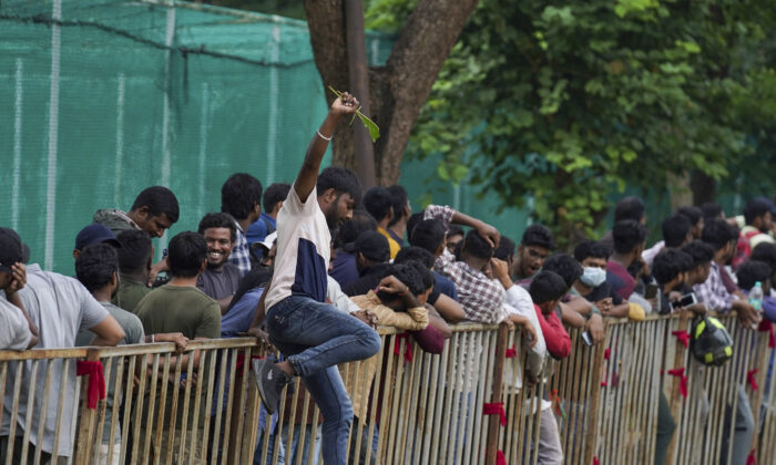 A man jumps a railing to take a break as people line up to buy tickets for the third Twenty20 cricket match between India and Australia at Gymkhana grounds in Hyderabad, India, on Sept. 22, 2022. (Mahesh Kumar A./AP Photo)