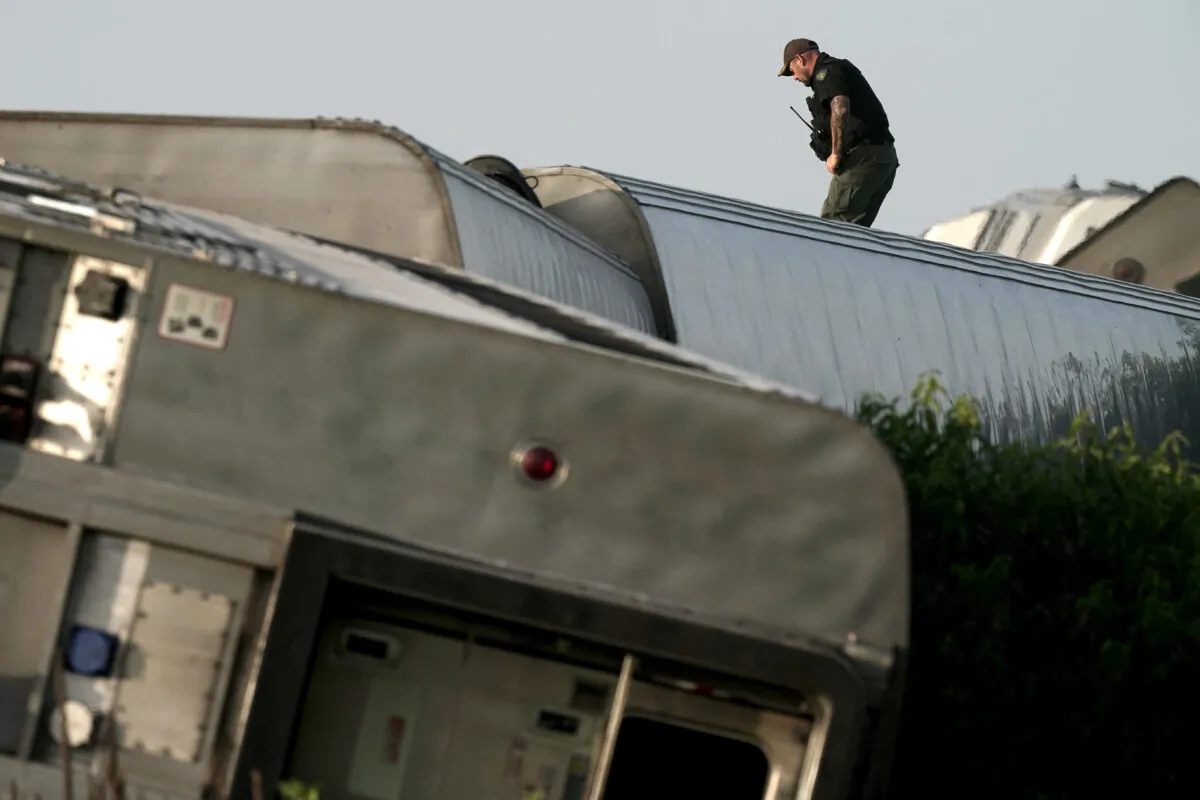A law enforcement officer inspects the scene of an Amtrak train that derailed after striking a dump truck near Mendon, Mo., on June 27, 2022. (Charlie Riedel/AP Photo)