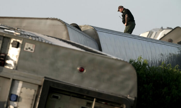 A law enforcement officer inspects the scene of an Amtrak train that derailed after striking a dump truck near Mendon, Mo., on June 27, 2022. (Charlie Riedel/AP Photo)