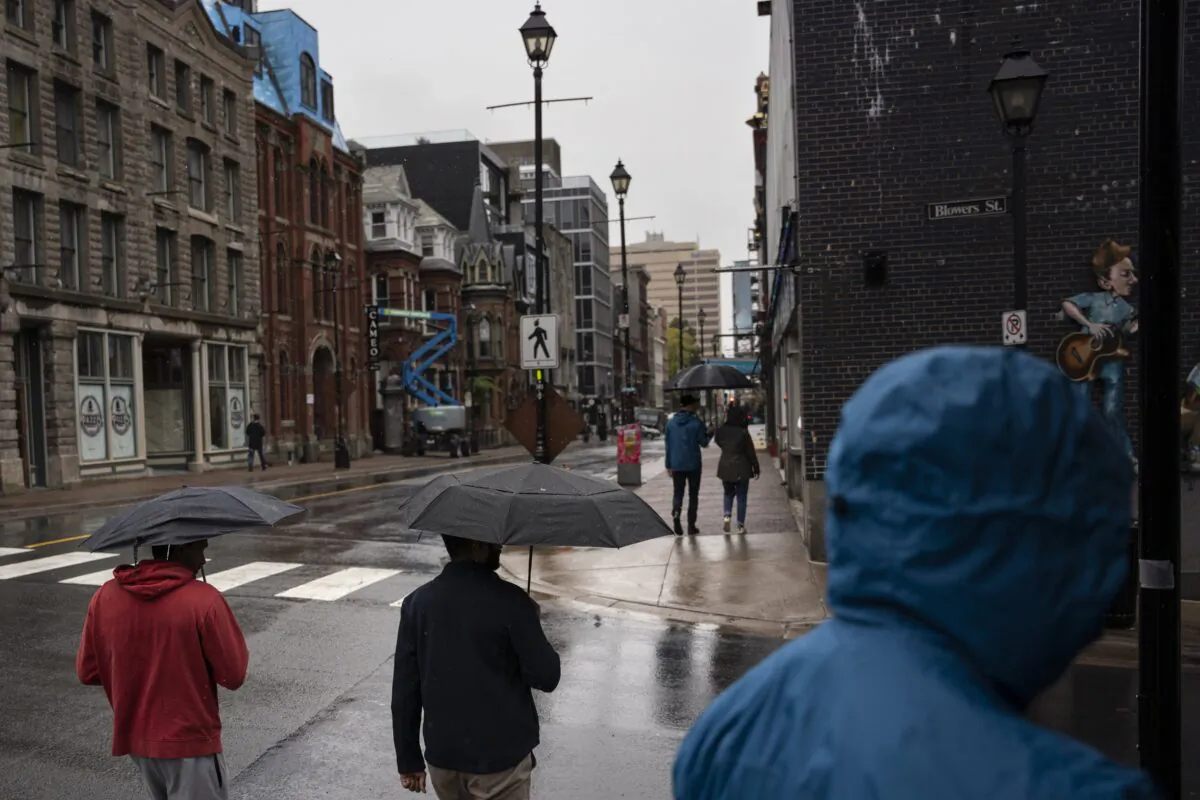 Pedestrians shield themselves from heavy rain falling ahead of Hurricane Fiona making landfall in Halifax, on Sept. 23, 2022. (The Canadian Press/Darren Calabrese)