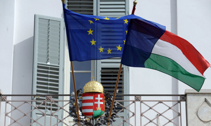 EU and Hungarian flags fly in front of a Hungarian crest at the presidental palace in Budapest, Hungary, on March 30, 2012. (Attila Kisbenedek/AFP via Getty Images)