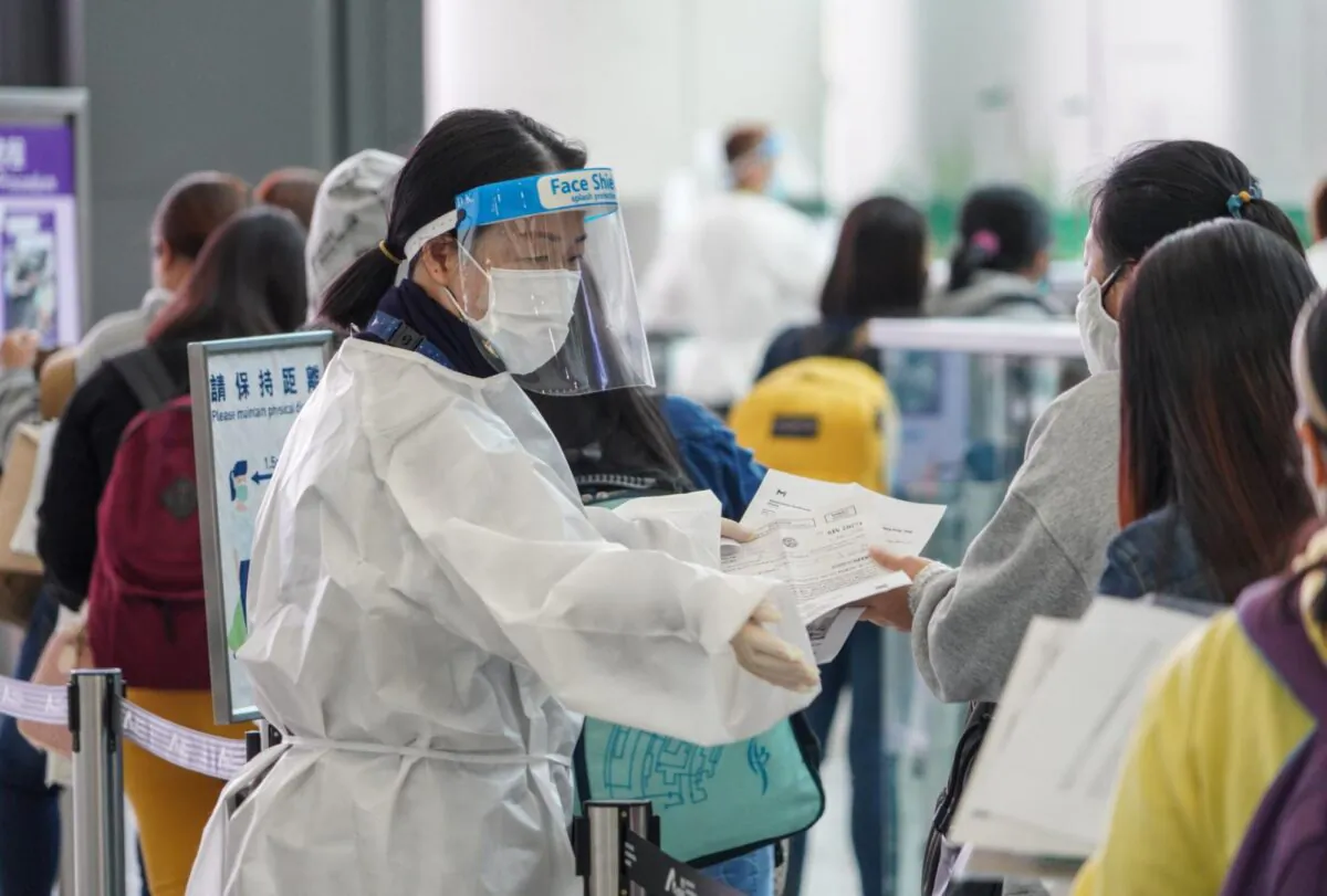 A quarantine officer  check the arrival passengers' Health Declaration Forms and other documents at the Hong Kong International Airport on Dec. 13, 2021. (Adrian Yu /The Epoch Times)
 
