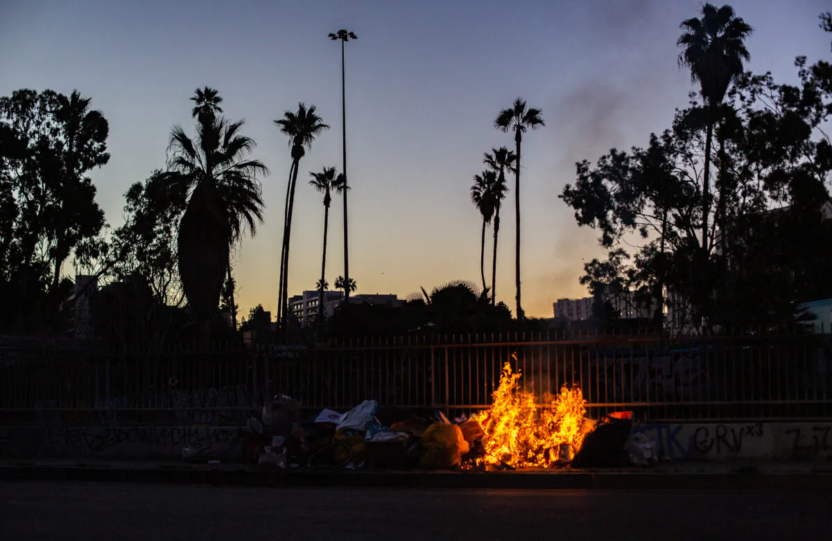 Fires lit within a homeless encampment fill the air with smoke in Los Angeles. (John Fredricks/The Epoch Times)