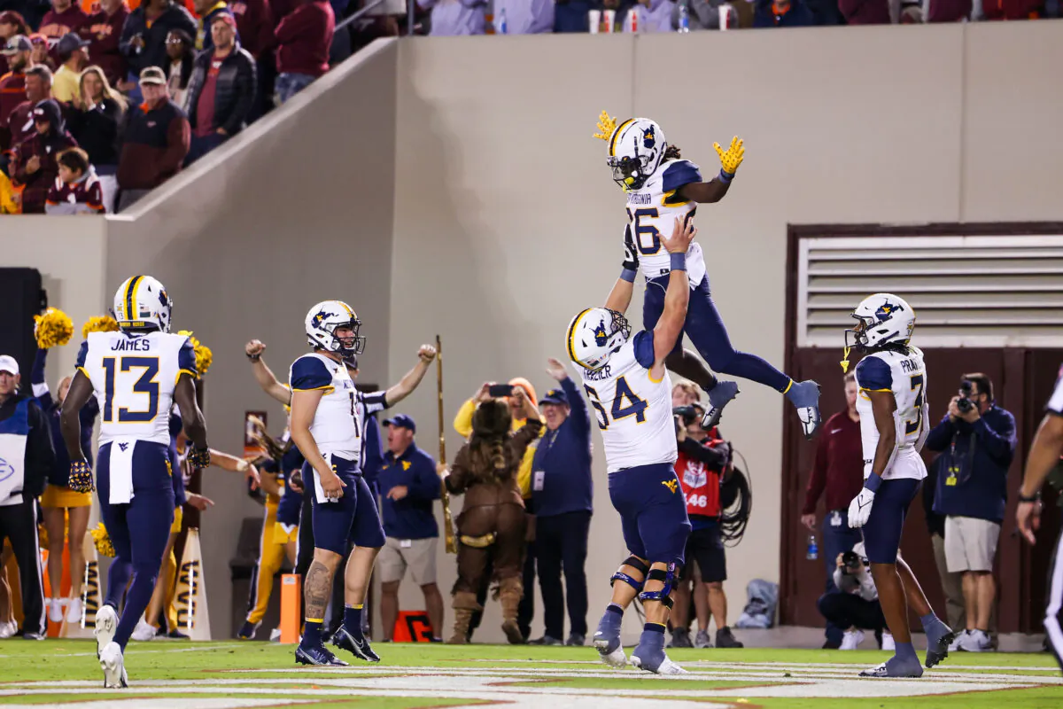 Linebacker Zach Frazier (54) of the West Virginia Mountaineers lifts up running back Justin Johnson Jr. (26) during the fourth quarter of the college football game between the Virginia Tech Hokies and the West Virginia Mountaineers at Lane Stadium in Blacksburg, VA, on Sept. 22, 2022. (Ryan Hunt/Getty Images)