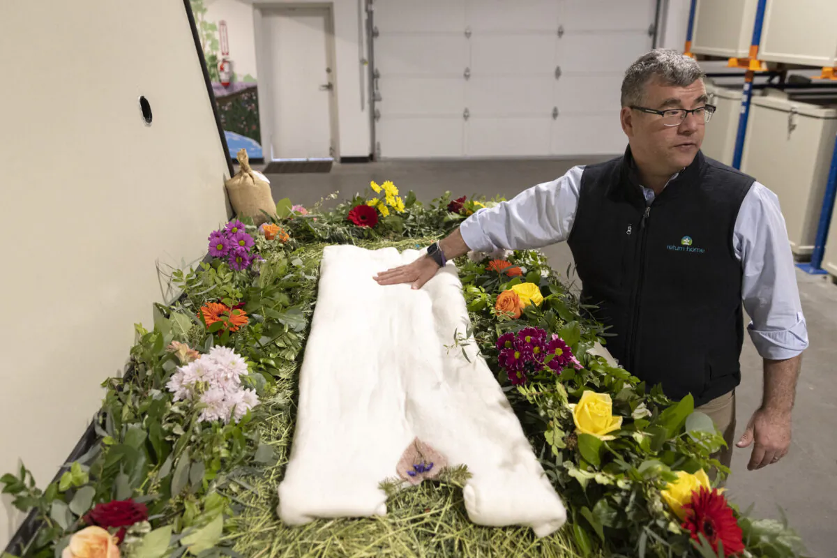 Return Home CEO Micah Truman shows a demonstration “vessel” for the deceased, decorated with flowers and compostable mementos on top of a bed, on March 14, 2022. (Jason Redmond/AFP via Getty Images)